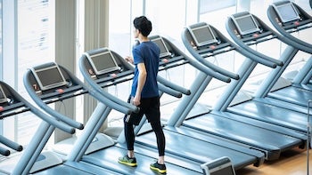 ジムのウォーキングマシンで運動する男性