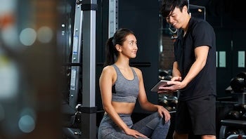 パーソナルトレーナーの説明を受ける女性