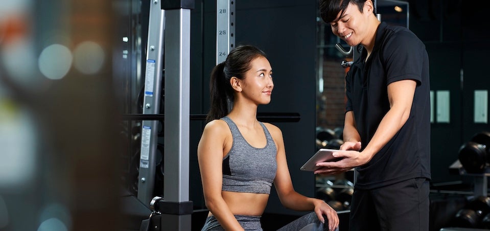 パーソナルトレーナーの説明を受ける女性